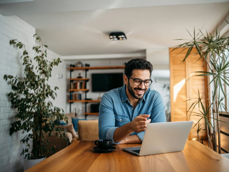 Portrait of a handsome man laughing while looking at laptop.