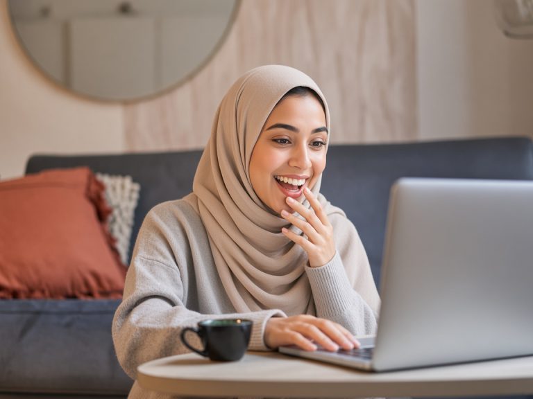 Portrait of asian woman in glasses, sitting with laptop and looking surprised, amazed by promotion on computer
