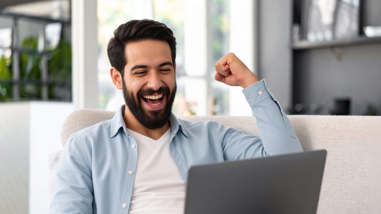 Young bearded man sitting on sofa at home using laptop computer, close up