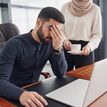 Guy feels bad. Woman and man in formal clothes working together indoors in the office by table